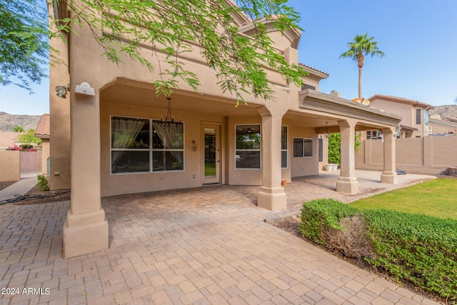 rear view of house featuring stucco siding, a patio area, and fence