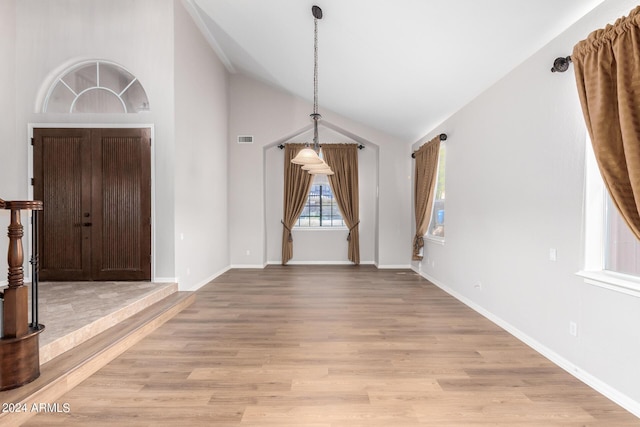 entryway with light wood finished floors, baseboards, and high vaulted ceiling
