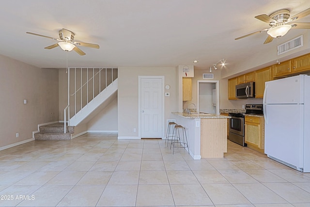 kitchen featuring a breakfast bar area, light tile patterned floors, stainless steel appliances, visible vents, and a peninsula