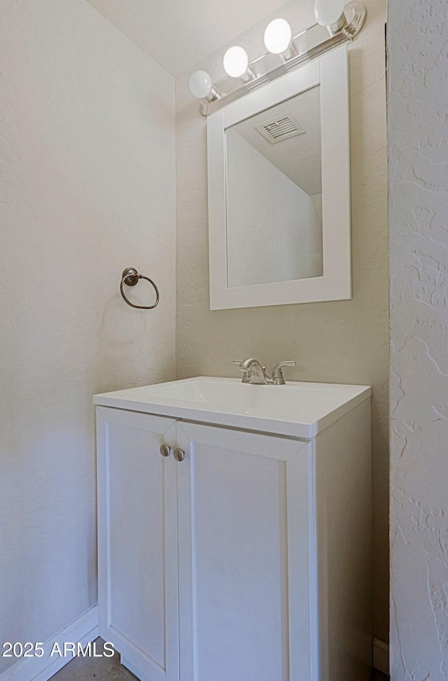 bathroom with a textured wall, visible vents, and vanity