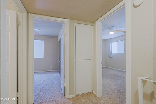 corridor featuring light carpet and baseboards