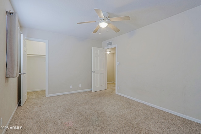 unfurnished bedroom with carpet floors, a walk in closet, a closet, visible vents, and baseboards