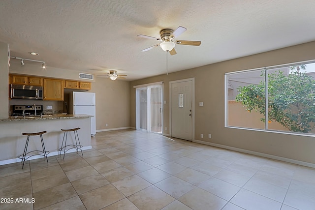 kitchen featuring light tile patterned floors, visible vents, appliances with stainless steel finishes, a textured ceiling, and baseboards