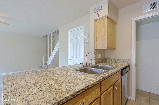 kitchen with light tile patterned flooring, a sink, visible vents, light stone countertops, and dishwasher