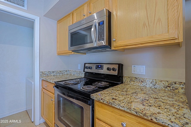 kitchen featuring visible vents, light stone counters, stainless steel appliances, light brown cabinets, and light tile patterned flooring