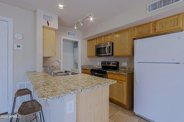 kitchen with stainless steel appliances, a breakfast bar, a sink, and visible vents