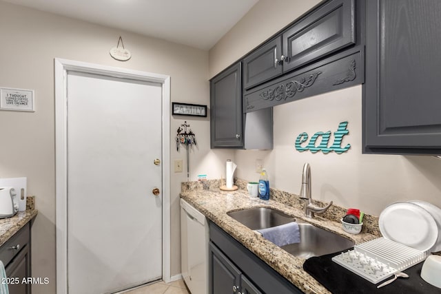 kitchen with light stone countertops, white dishwasher, gray cabinets, and a sink