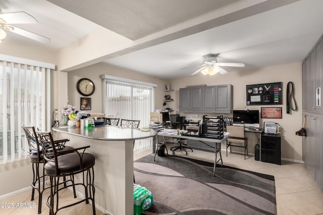 kitchen featuring ceiling fan, a breakfast bar, a peninsula, gray cabinets, and light tile patterned flooring