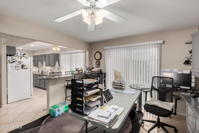 office space with light tile patterned floors, a sink, a ceiling fan, and a healthy amount of sunlight