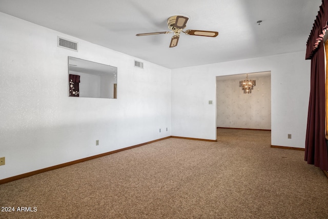 carpeted empty room featuring ceiling fan with notable chandelier