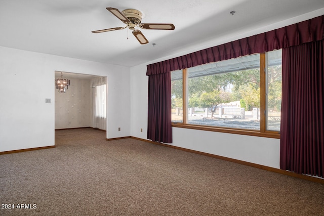 carpeted spare room with ceiling fan with notable chandelier