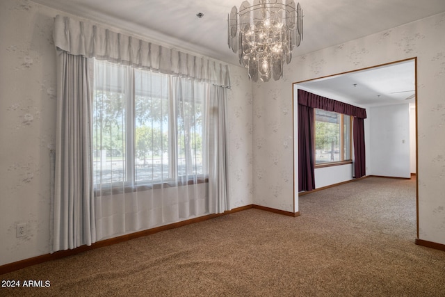 carpeted empty room featuring an inviting chandelier