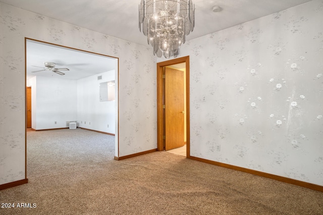 carpeted empty room featuring ceiling fan with notable chandelier