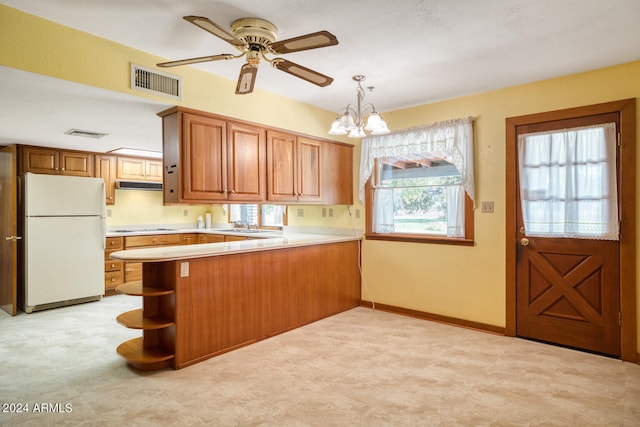 kitchen featuring kitchen peninsula, a wealth of natural light, white fridge, and decorative light fixtures