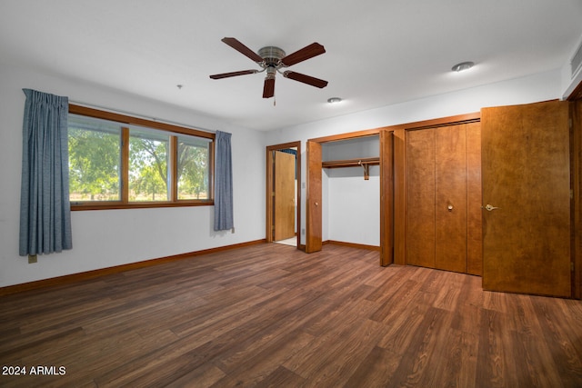 unfurnished bedroom featuring dark hardwood / wood-style floors, ceiling fan, and multiple closets