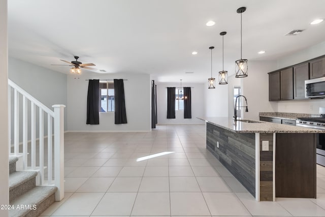 kitchen with an island with sink, stainless steel appliances, sink, dark brown cabinetry, and ceiling fan