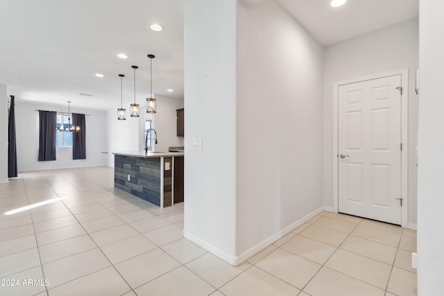 corridor with light tile patterned flooring and an inviting chandelier