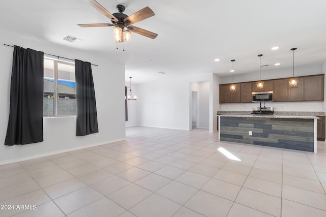 kitchen with light stone countertops, dark brown cabinets, ceiling fan with notable chandelier, and light tile patterned flooring