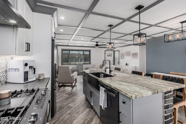 kitchen with a sink, open floor plan, appliances with stainless steel finishes, exhaust hood, and ceiling fan