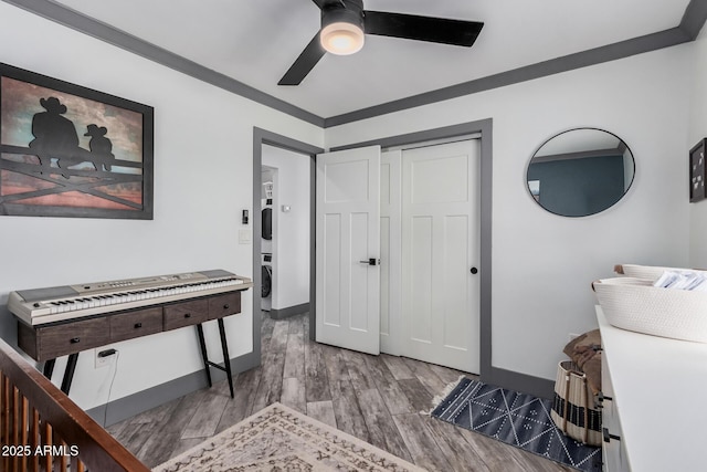 interior space with a ceiling fan, crown molding, wood finished floors, and baseboards