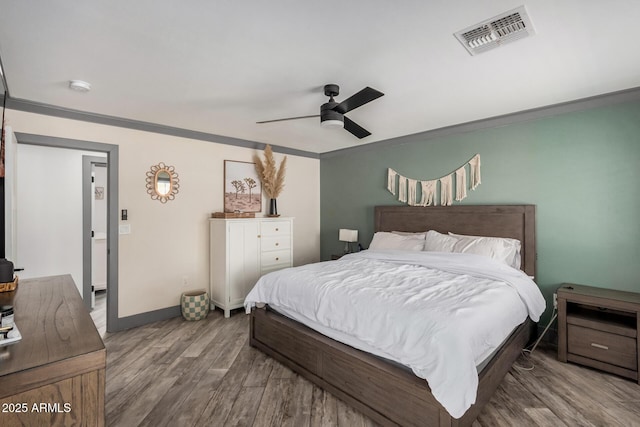 bedroom with visible vents, ornamental molding, wood finished floors, baseboards, and ceiling fan