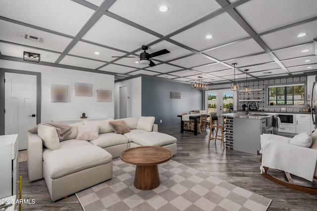 living area featuring ceiling fan, dark wood finished floors, indoor wet bar, recessed lighting, and coffered ceiling