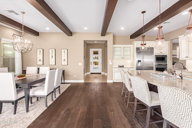 dining space featuring dark wood-type flooring, a chandelier, sink, and beam ceiling