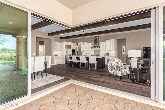 living room featuring wood-type flooring, beamed ceiling, and a notable chandelier