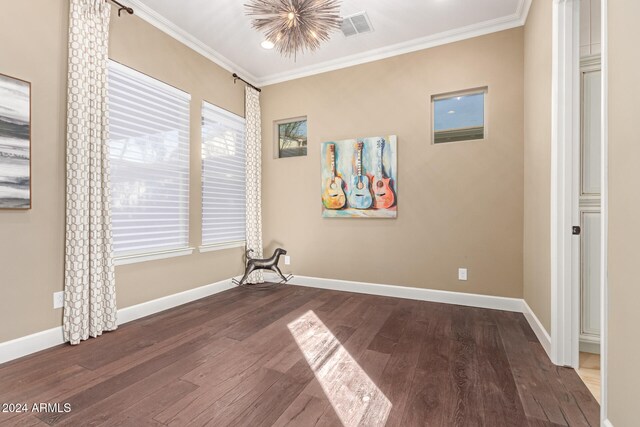 spare room featuring a chandelier, hardwood / wood-style flooring, and crown molding