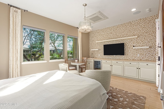 bedroom featuring a chandelier, beverage cooler, and light wood-type flooring