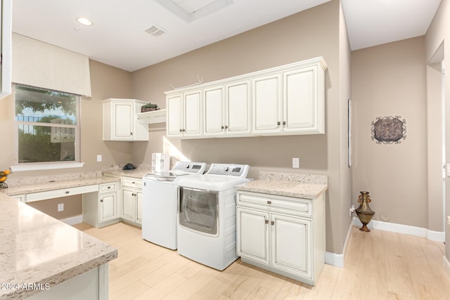 laundry area featuring washer and clothes dryer, cabinets, and light hardwood / wood-style flooring