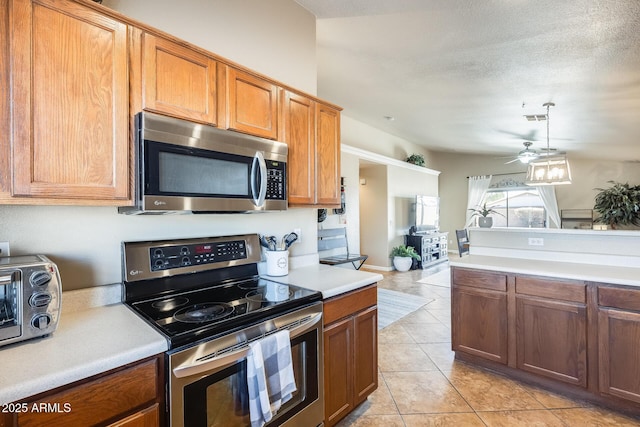 kitchen with light tile patterned floors, ceiling fan, appliances with stainless steel finishes, hanging light fixtures, and a textured ceiling