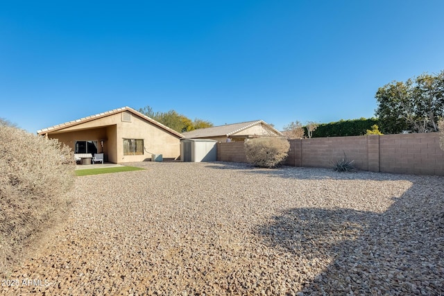 back of property featuring a patio and a storage unit