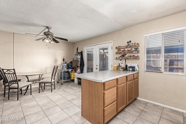 kitchen featuring french doors, a textured ceiling, light tile patterned floors, kitchen peninsula, and ceiling fan