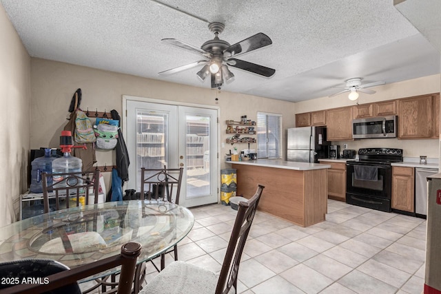 kitchen with appliances with stainless steel finishes, light tile patterned floors, a textured ceiling, and french doors