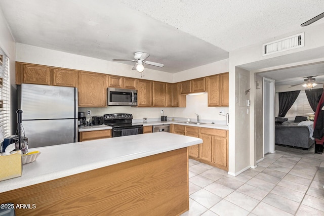 kitchen featuring sink, light tile patterned floors, ceiling fan, appliances with stainless steel finishes, and a textured ceiling