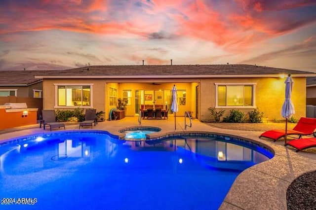 pool at dusk with an in ground hot tub and a patio