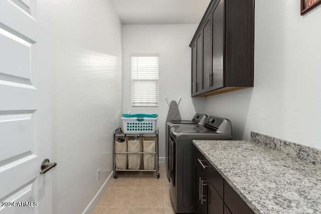 washroom with washing machine and clothes dryer, light tile patterned floors, and cabinets