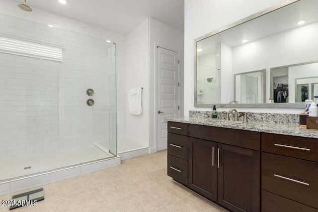 bathroom with tile patterned flooring, walk in shower, and vanity