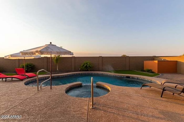 pool at dusk featuring an in ground hot tub and a patio