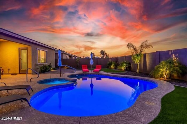 pool at dusk featuring an in ground hot tub