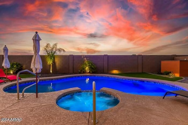 pool at dusk featuring an in ground hot tub and a patio