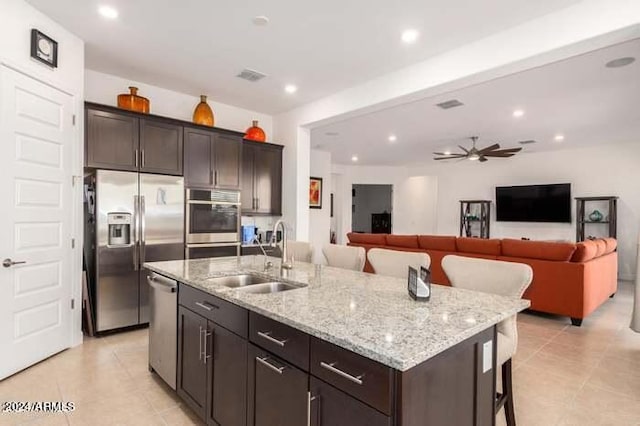 kitchen featuring dark brown cabinetry, stainless steel appliances, sink, a breakfast bar area, and a center island with sink