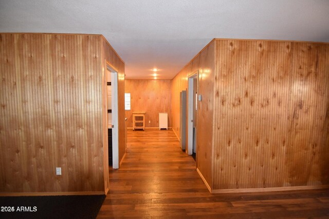 corridor with wood walls, hardwood / wood-style flooring, and baseboards