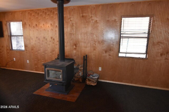 details featuring a wood stove, carpet, wooden walls, and baseboards