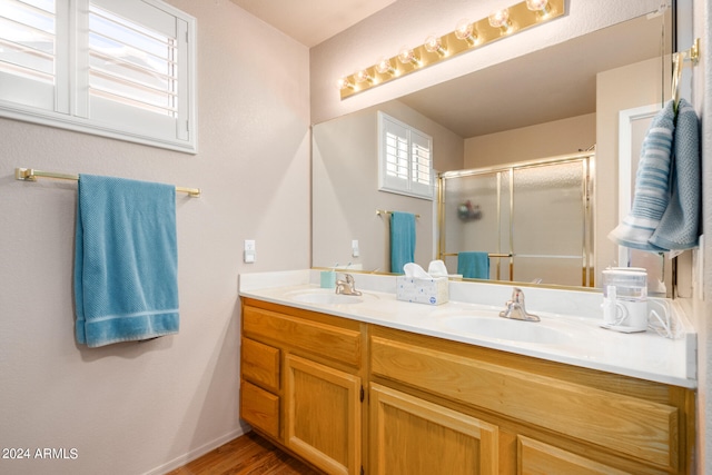 bathroom featuring hardwood / wood-style flooring, a shower with door, and vanity