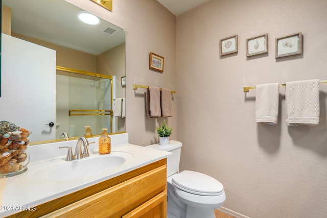 bathroom featuring vanity, toilet, and an enclosed shower