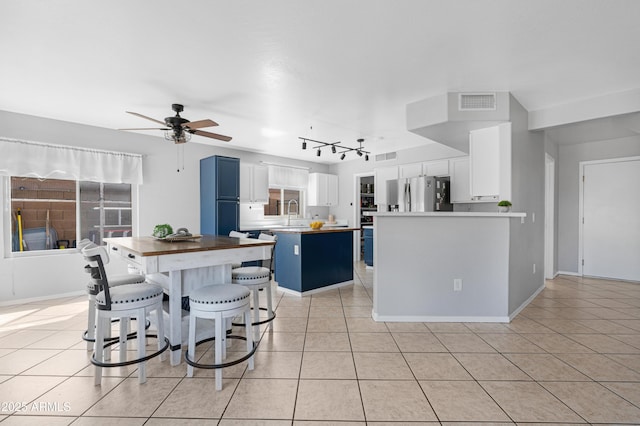 kitchen featuring blue cabinetry, stainless steel fridge, and light tile patterned flooring