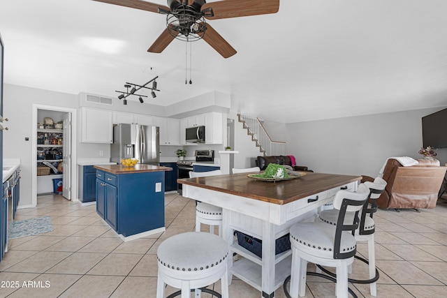 kitchen with visible vents, wooden counters, light tile patterned floors, appliances with stainless steel finishes, and blue cabinets