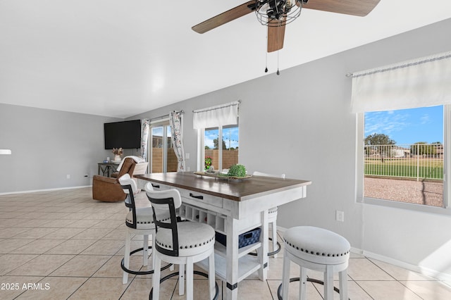 dining space with light tile patterned floors, a ceiling fan, and baseboards